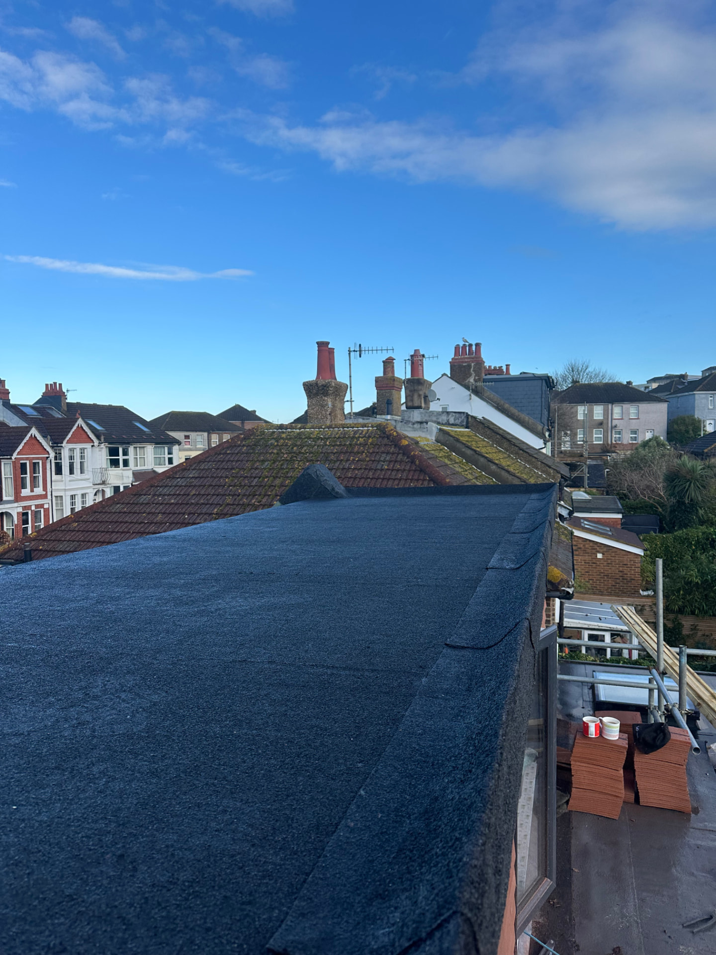 New charcoal mineral felt flat roof on a residential extension beside pitched tiled roofs